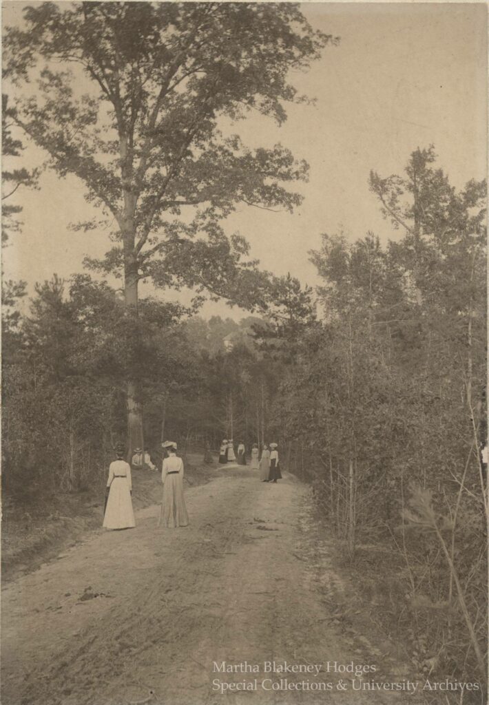 Historical Peabody Park image of people walking along a path in the park. Circa 1900 - 1910.